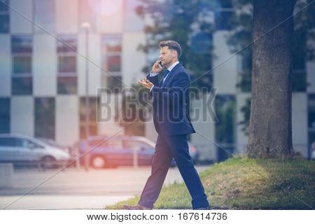 Businessman using mobile phone while walking on road