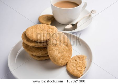 spicy fried mathri or mathari which is an indian snack served with a cup of tea, selective focus