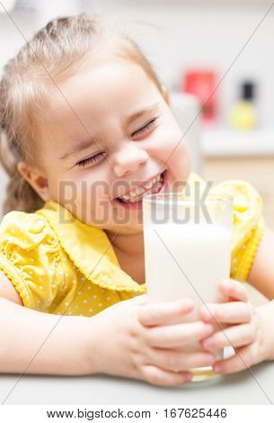Child girl drinking milk at the kitchen