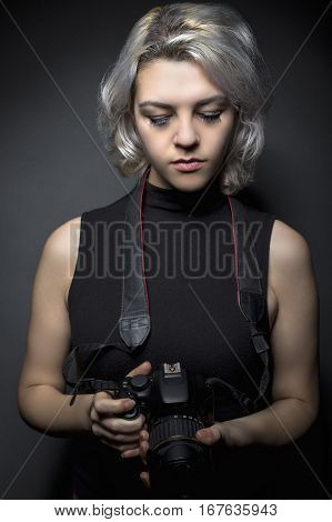 Female professional or amateur photographer holding a dslr camera. This photographic gear is used by both self employed artists and journalists or for tourism and hobbies.