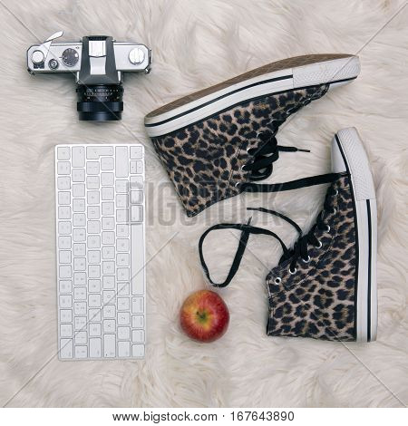 Lifestyle Flat Lay with leopard print boots old camera keyboard and apple on a fur rug