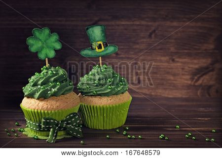 Cupcake with clover cakepick on a wooden background