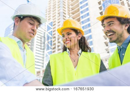 Architects and civil engineers with ground plot on construction site of highrise building