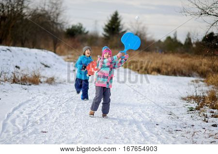 Two children of younger school age boy and girl spend time in winter day with pleasure. Children have thought up the winter tennis. Instead of a ball - a snowball. To children it is very cheerful.