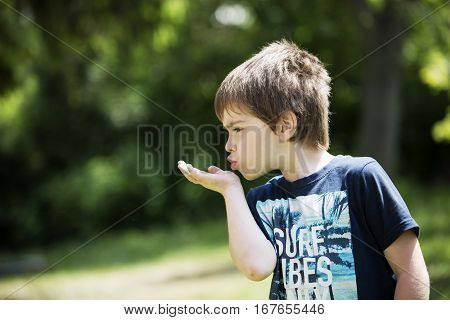 Playing boy on lawn. Funny white child with baseball cap. Young lad boy sends a kiss. Youngster with thoughtful face. In captivity of activity. Son spends leisure time activities in house garden.