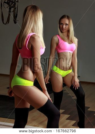 Fit blonde girl in bikini standing in front of mirror