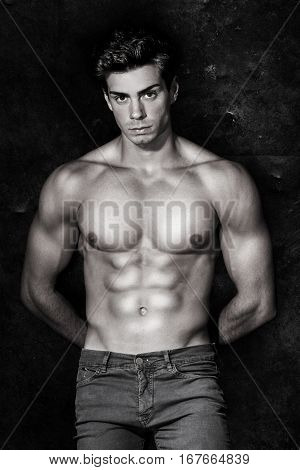 Italian model muscular man. A young Italian boy shirtless posing on a grunge background. Muscular and athletic. Well-defined muscles. Black and white