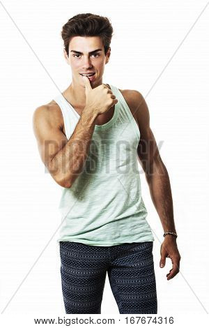 Handsome muscle and provocative man thumb on his lips. In tank top, sculpted physique. White background