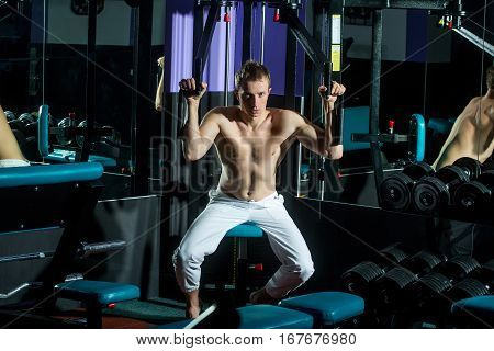handsome muscular guy or macho man with sexy torso and body training in sport gym on black trainer of weight lifting