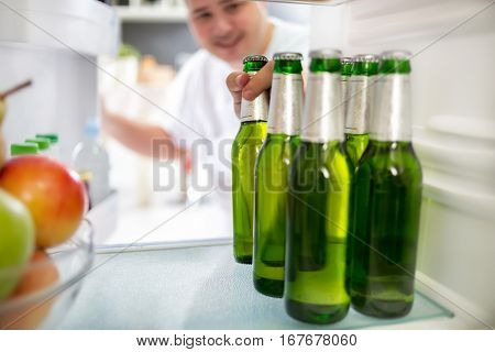 Boy take bottle of cold beer from refrigerator