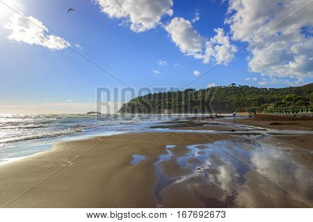 Summer seaside.Gargano coast: Portonuovo beach (Vieste). Sandy  beach with waves dominated by cloud crossed by sunbeams.
