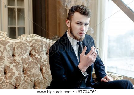 Close up portrait picture of a handsome young business man  smoking a cigarette