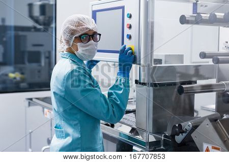 scientist in glasses and lab suit is checking readings of machine look at camera