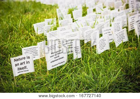 ROTTERDAM THE NETHERLANDS - AUGUST 23 2014: Art instalation in Rotterdam. Lots of tiny banners with qoutes about nature are thrust into green lawn. Save the planet concept