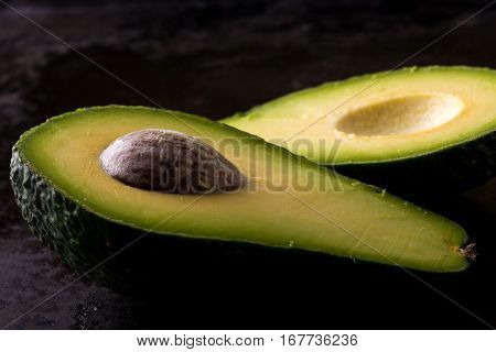 Single Avocado Severed In Half On Black Tray