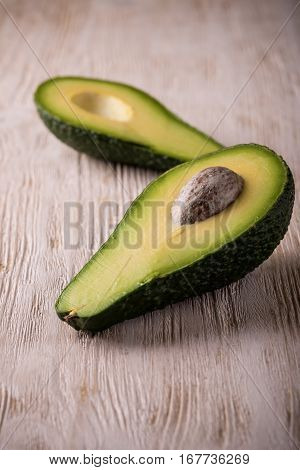 Single Avocado Severed In Half On White Wooden Board