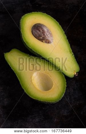Top View On Single Avocado Severed In Half On Black Tray