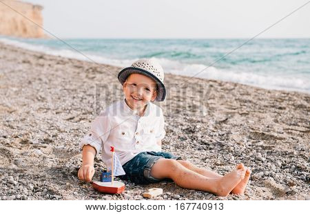 Baby boy playing wooden ship on the beach.Portrait of a child.