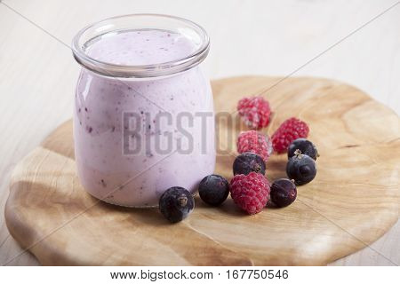 Smoothies with frozen berries black currants and raspberries in jar on a wooden stand.