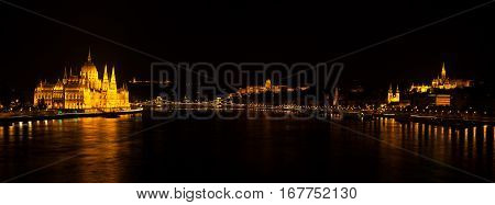 Panoramic Night View On Hungarian Parliament Building Located At The Bank Of The Dunabe River With F