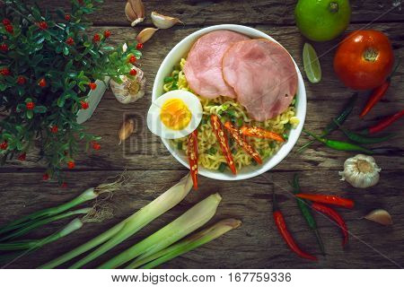 Ramen noodles with vegetables egg ham on old rustic wooden background vintage style.