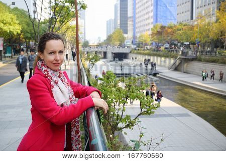 Woman in red coat standing near barrier and watching to Hangang river in Seoul