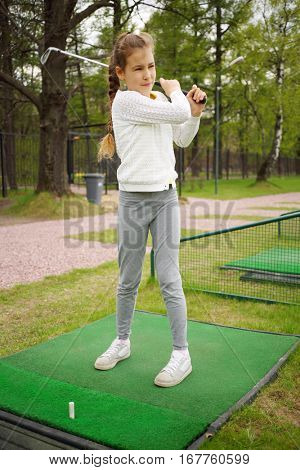 Girl with cammock after hit on green golf course at spring day