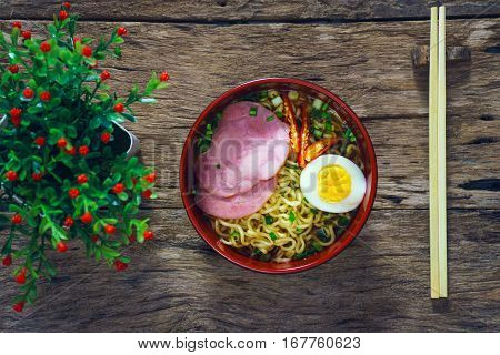 Ramen noodles with vegetables egg ham on old rustic wooden background vintage style.