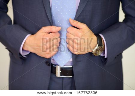 Hands of man in suit with tie, leather belt and wristwatch in studio, noface