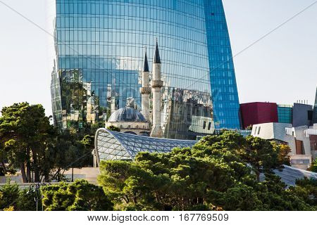 BAKU, AZERBAIJAN - OCT 4, 2016: Mosque of the Martyrs (Sehidler Mescidi Mosque, Turkish Mosque) with the Flame Towers skyscraper in the background in Baku on Oct 4, 2016, Azerbaijan, at sunset. 