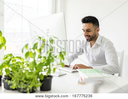 Young confident man working in modern office full of light