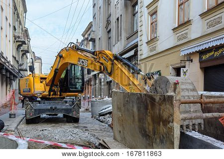 Ukraine Lviv - December 17 2016: Repair of the aqueduct in the city center of Lviv on the narrow street. Construction machinery. Excavation work at the construction site.