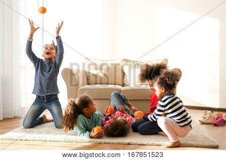 Five cute African girls playing with oranges on floor