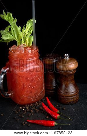 Bloody Mary or Bloody Ceasar with celery in mason jar rimmed with black pepper