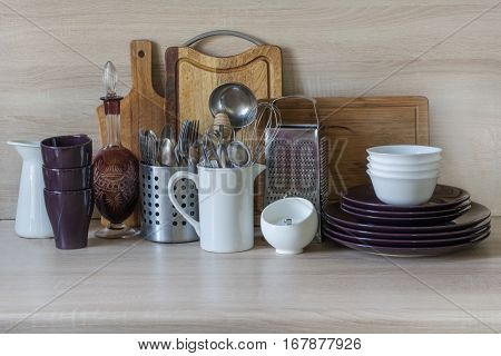 Kitchen still life as background for design. Crockery tableware and other different stuff on wooden table-top. Image with copy space.
