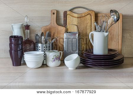 Crockery tableware utensils and other different stuff on wooden table-top.Kitchen still life as background for design. Image with copy space.