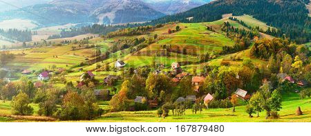 Small village on alpine hills in spring. Spring colors of Alps. Spring panoramic landscape of sunny alpine morning. Country spring background. Beautiful rural scene.