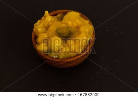 Piccalilli relish in a wooden bowl on a dark slate background.