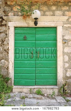 green wooden door with brass handle and knocker in Risan, Montenegro
