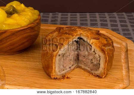 Piccalilli relish in a wooden bowl on a board.