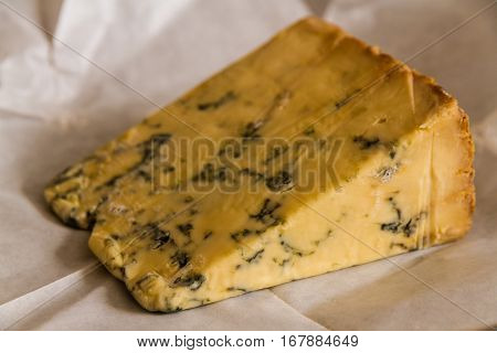stilton cheese resting on unwrapped greaseproof paper.