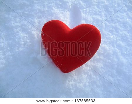 Red plush heart in snow in the winter