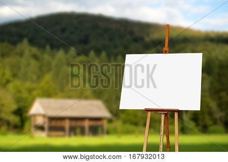 Blank painter artist canvas on easel with mountain in background copy space for artistic picture or painting