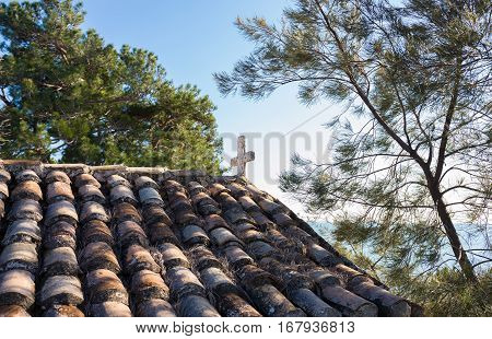 white stone cross on a tile roof of chapel