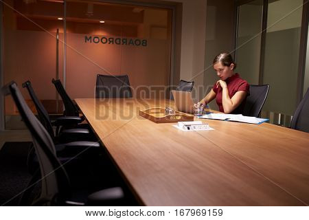 Young white businesswoman working alone late in an office