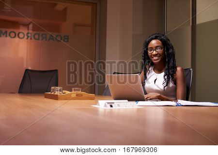 Young black woman working late in office smiling to camera