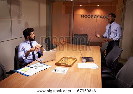 Businessman talks to colleague late in office, elevated view