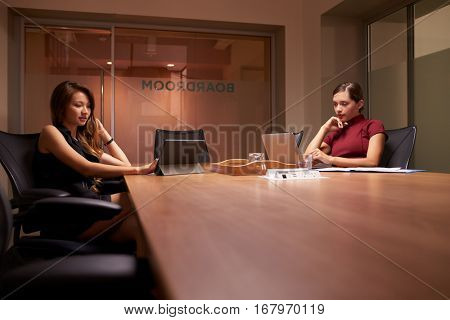 Two businesswomen working late in office using computers