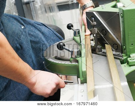 Craftsman working on frame in frameshop. Professional framer hand holding frame angle. Top view.