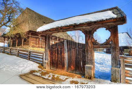 Traditional wooden house and gate of the village museum from Baia Mare, in winter season - Transylvania, Romania